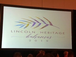 A large screen with the lincoln heritage logo on it.