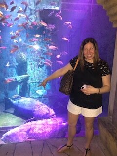 A woman standing in front of an aquarium holding a remote.