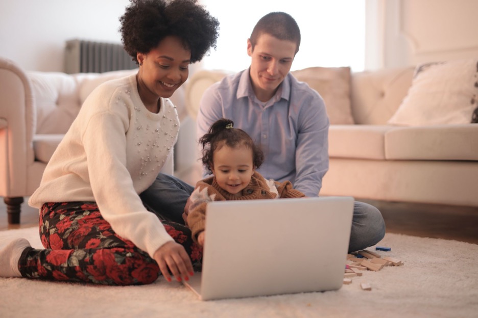 A family sitting on the floor looking at a laptop