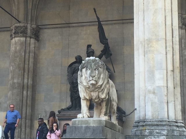 A statue of a lion and people in front of a building.
